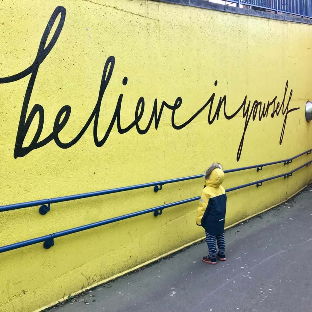 A child looking up at a message that says ‘believe in yourself"